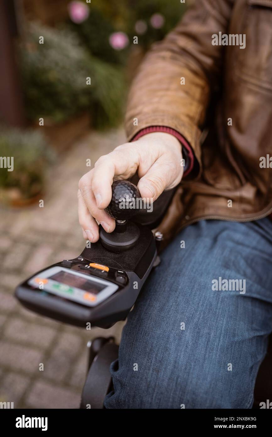 Section médiane de l'homme âgé ayant une déficience qui fait fonctionner un fauteuil roulant motorisé dans la cour arrière Banque D'Images