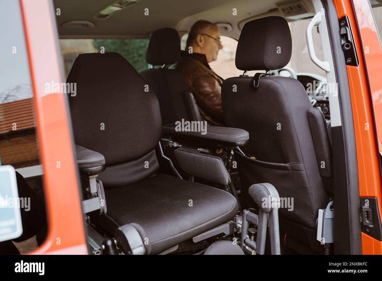 Fauteuil roulant motorisé contre un homme handicapé assis dans une camionnette Banque D'Images