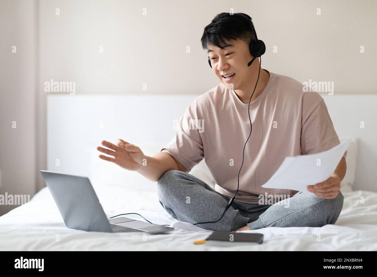 Homme asiatique travaillant à domicile, avoir des réunions en ligne avec des collègues Banque D'Images