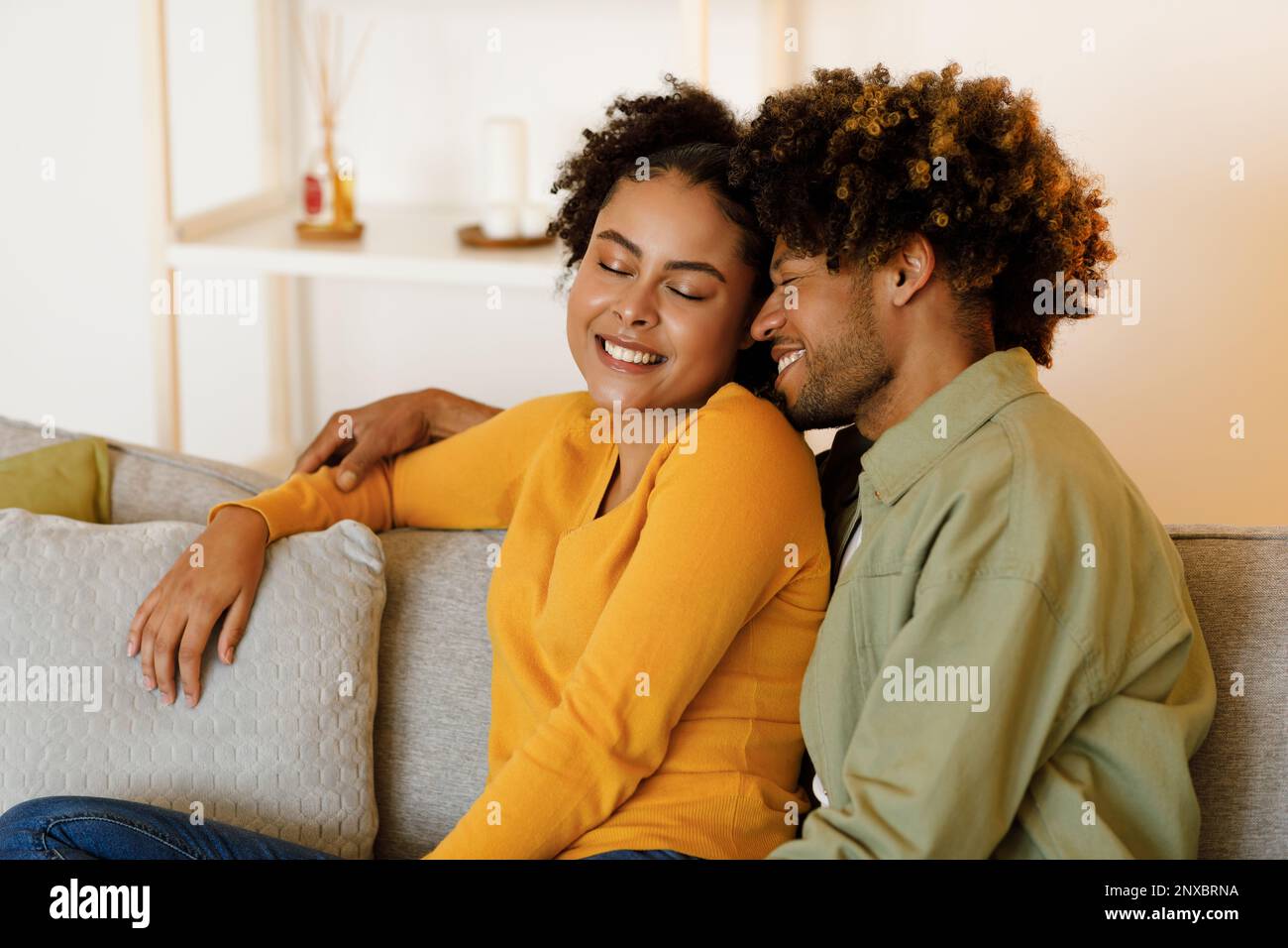 Un heureux couple afro-américain qui se tient assis sur un canapé à la maison Banque D'Images
