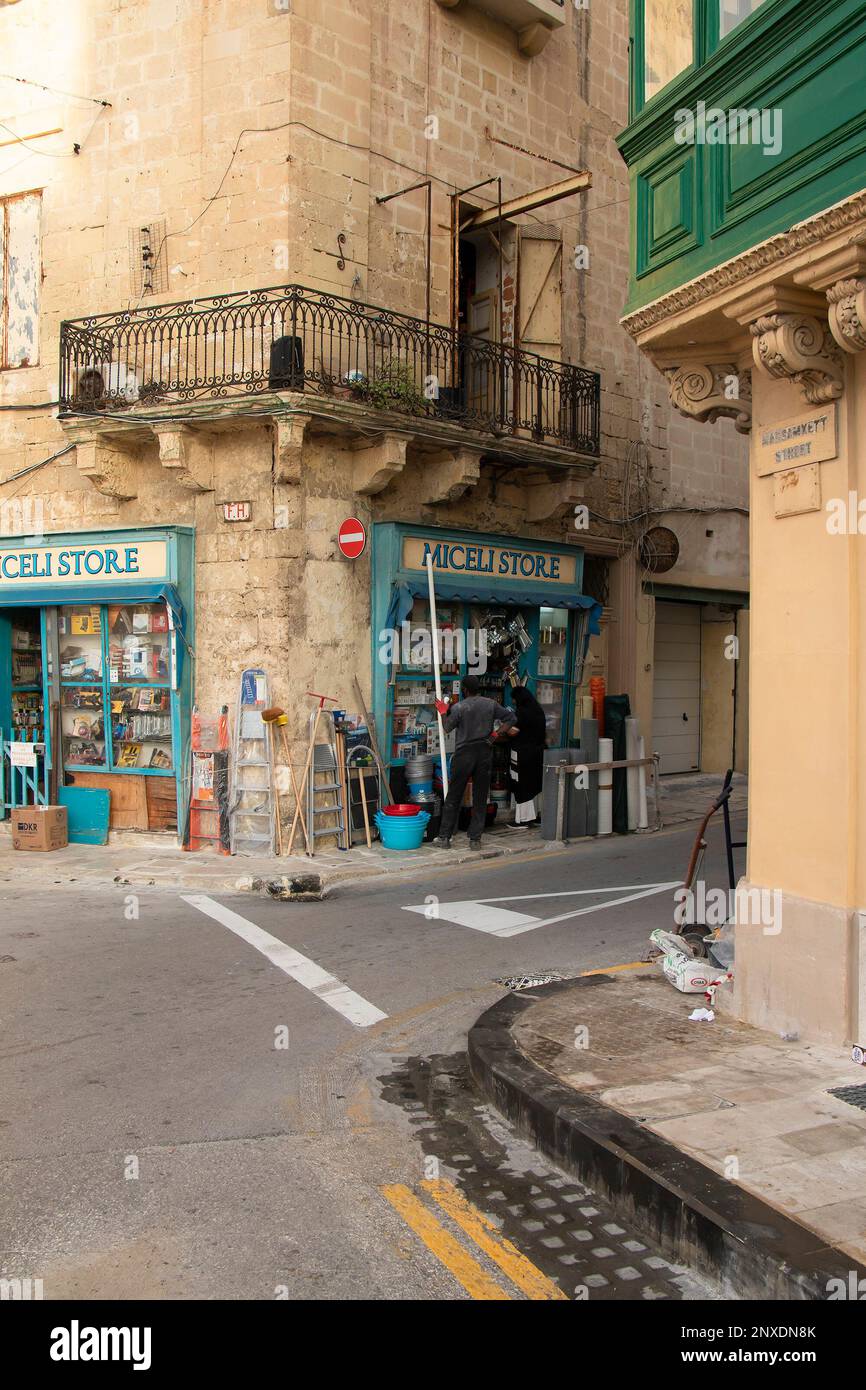 Valletta, Malte - 11 novembre 2022: Magasin de quincaillerie d'angle pour la construction de fournitures dans la maison calcaire avec un balcon au-dessus Banque D'Images