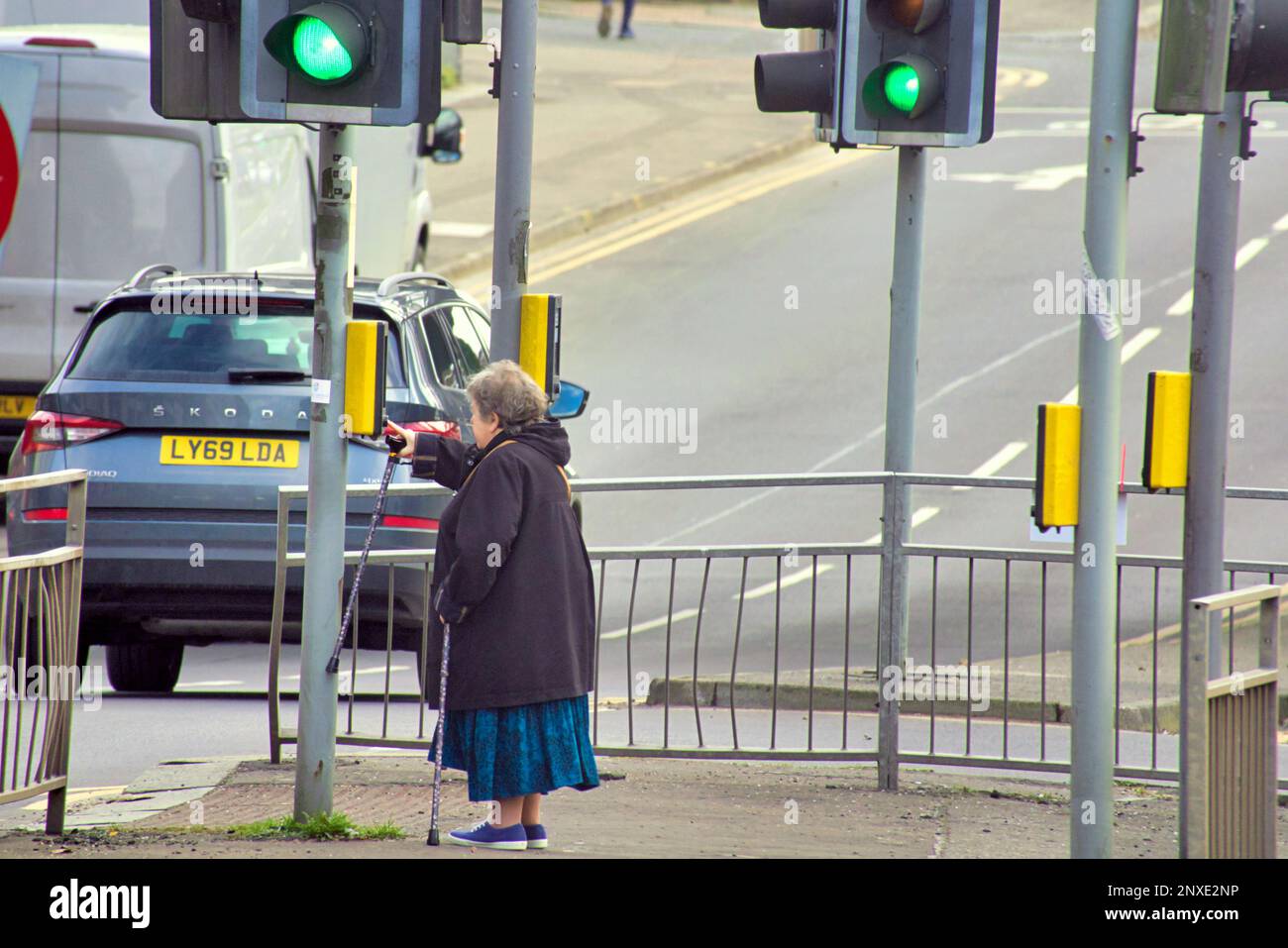 Femme appuyant sur le bouton aux feux de signalisation anniesland traverser Glasgow, Écosse, Royaume-Uni Banque D'Images
