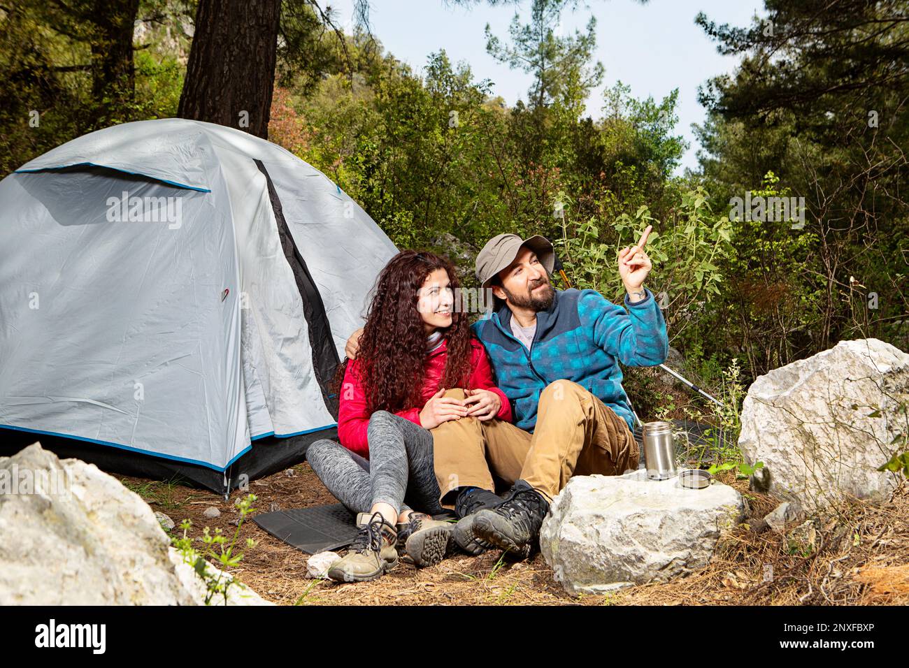 Jeunes touristes couple voyageurs avec abri de tente assis dans la nature, en utilisant le smartphone Banque D'Images