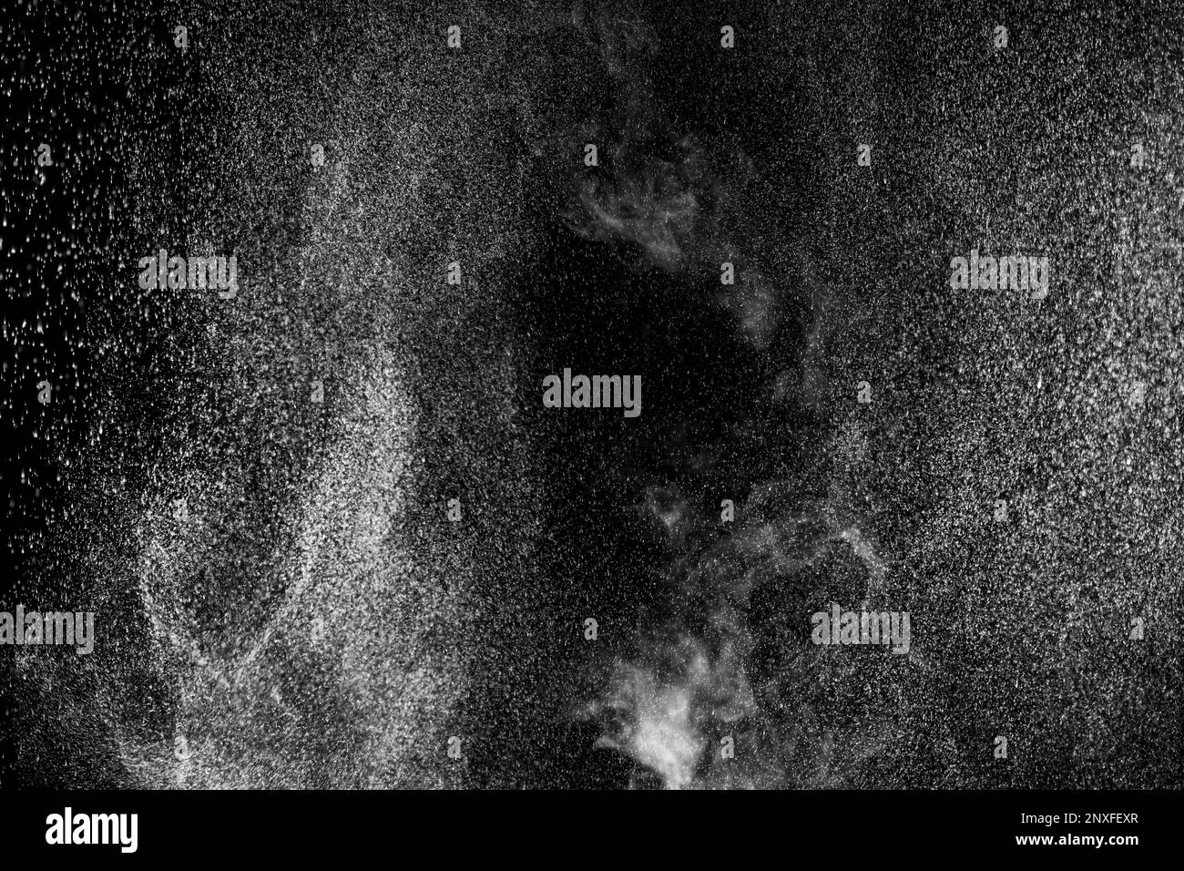 Vapeur blanche bouclés qui s'élève et projection d'eau dans différentes directions isolée sur fond noir. Évaporation du liquide et du condensateur Banque D'Images