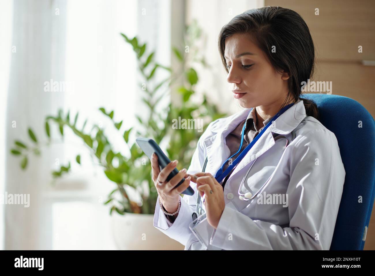Médecin lisant les messages texte du patient sur le smartphone Banque D'Images