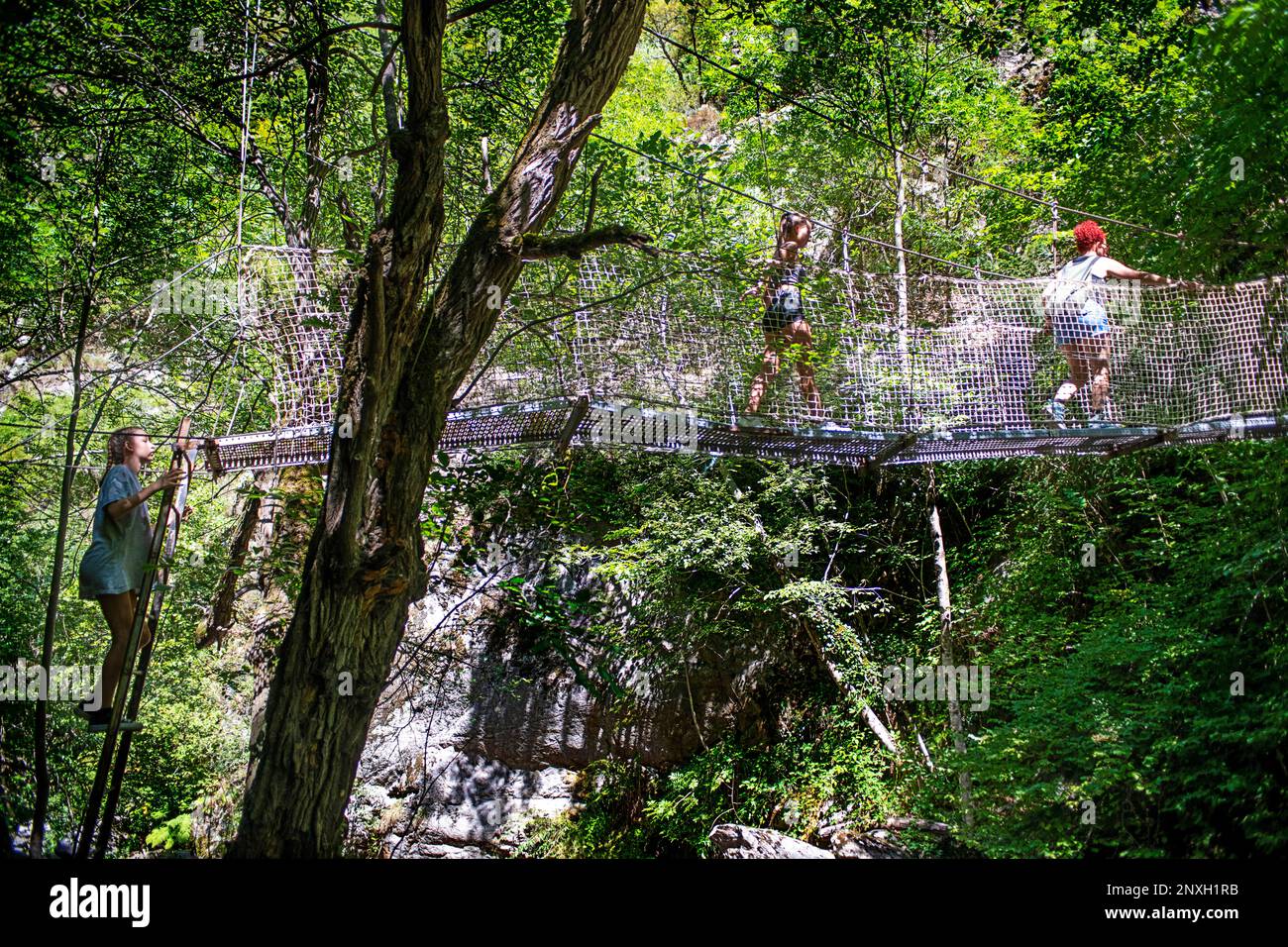 Randonneur traversant un pont suspendu métallique sur un sentier de randonnée traversant les Gorges de la Carança, Pyrénées-Orientales, Languedoc-Roussillon, France. Le Carançà G. Banque D'Images