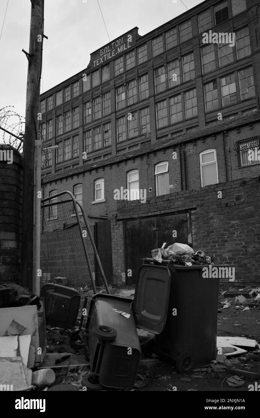 Bolton textile Mill (rue Cawdor, Farnworth) avec des maisons en terrasse et des poubelles à déchets ménagers au premier plan. Angleterre, Royaume-Uni Banque D'Images