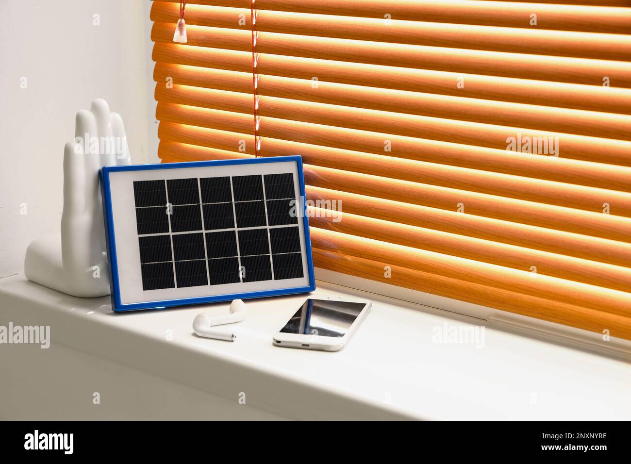 Panneau solaire portable pour charger le téléphone portable et les écouteurs sur le rebord de la fenêtre dans la chambre Banque D'Images