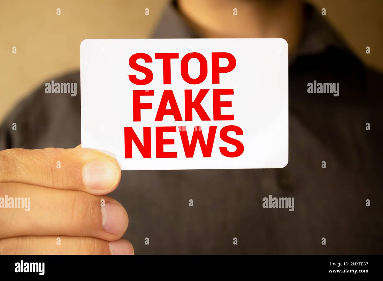 Femme tenant le mégaphone et la plaque avec le texte ARRÊTER LES FAUSSES NOUVELLES sur fond sombre. Banque D'Images