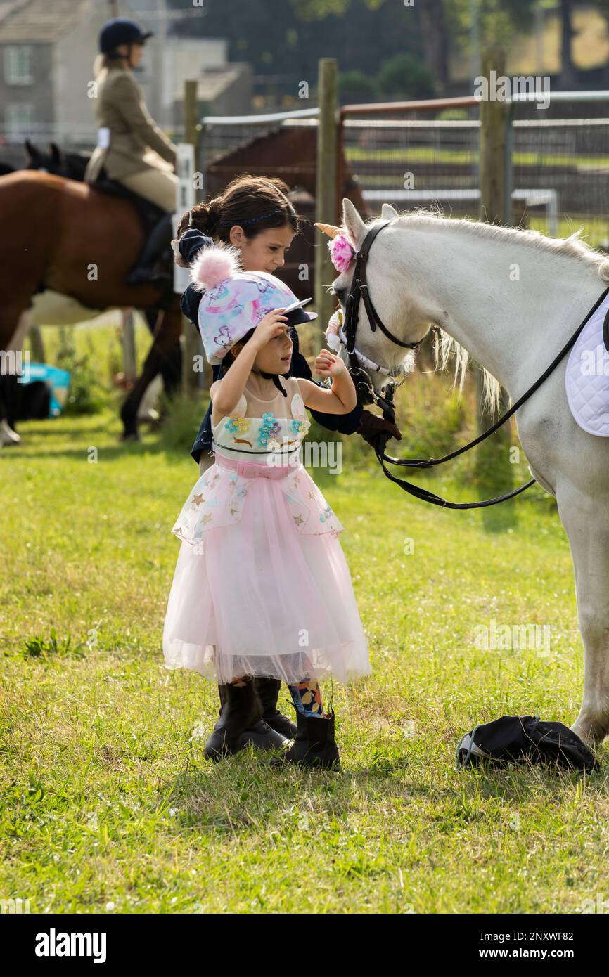 Petite fille en robe tutu rose défilant avec son poney blanc au Weardale Show, St John's Chapel, Weardale, County Durham Banque D'Images