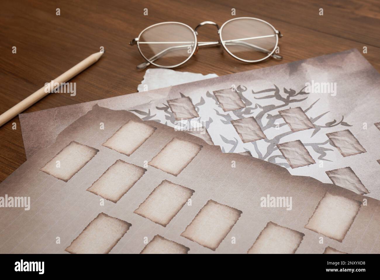 Papiers avec gabarits d'arbre de famille, crayon et lunettes sur table en bois, gros plan Banque D'Images