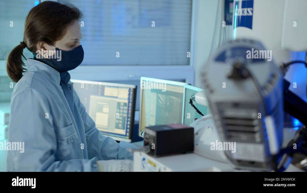 Le processus de travail. Films. Une femme dans un uniforme spécial dans une robe de chambre et un masque travaille à une production complexe spéciale à un esprit de clavier Banque D'Images