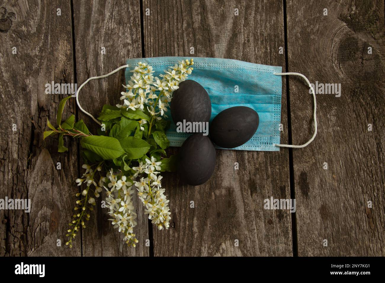 Masque médical et œuf noir peint le jour de Pâques sur une vieille table en bois pendant la pandémie Banque D'Images