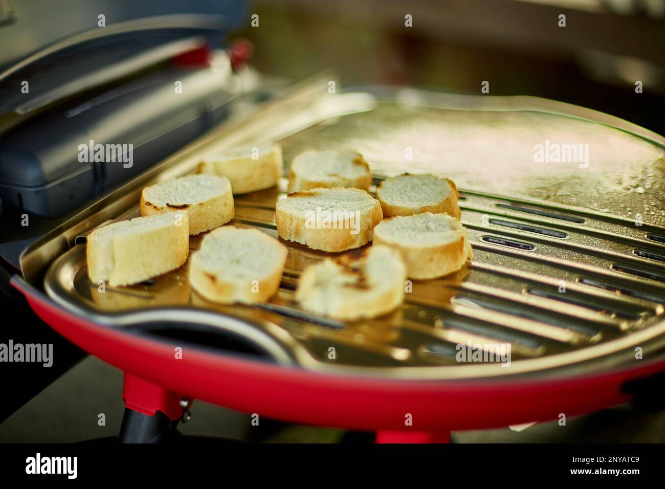 Préparer le petit déjeuner avec du pain, rôtir la bruschetta sur le barbecue  à gaz extérieur dans l'arrière-cour, petit déjeuner sur le grill,  pique-nique familial d'été, nourriture Photo Stock - Alamy