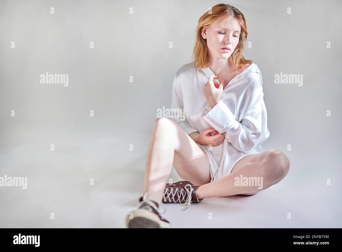 Jeune femme assise en studio avec la lumière du soleil Banque D'Images