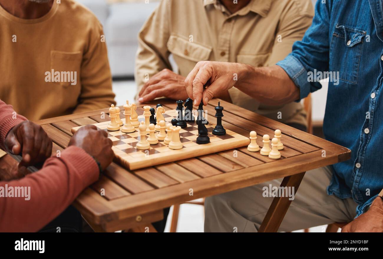 Mains, échecs et amis dans les jeux de société sur table en bois pour la compétition stratégique, le mouvement tactique ou la décision. Main d'un joueur de stratégie qualifié tenant Banque D'Images