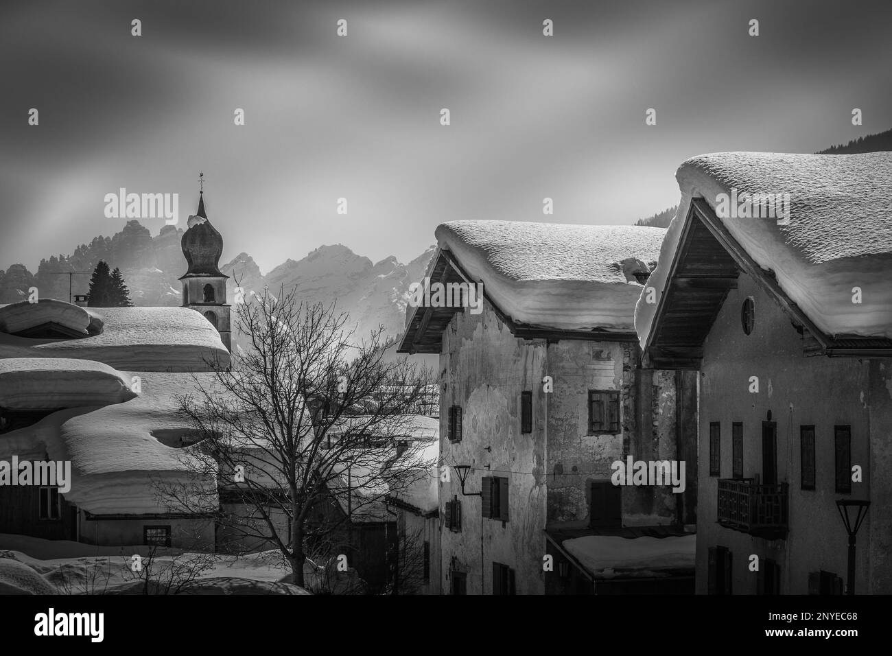 Vue en noir et blanc sur les maisons du petit village des Dolomites aux toits enneigés Banque D'Images