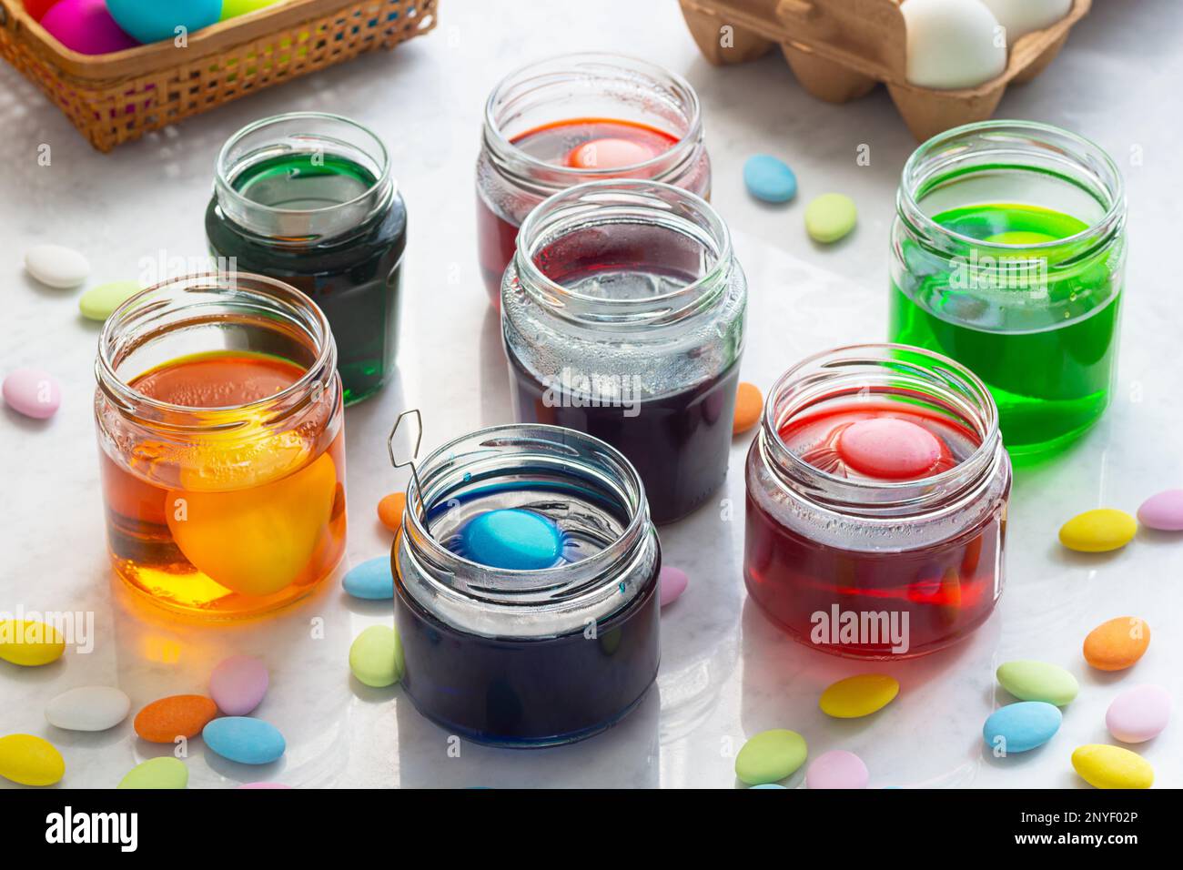 Teindre les œufs de Pâques dans des jarres colorées en verre avec une Candy de Pâques multicolore sur un comptoir en marbre Banque D'Images