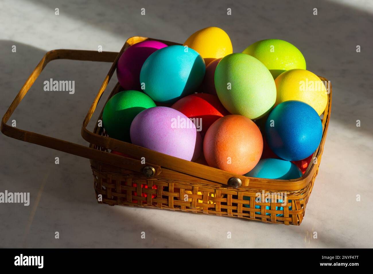 Panier rempli d'œufs de Pâques colorés en couleurs arc-en-ciel pour les vacances de printemps Banque D'Images