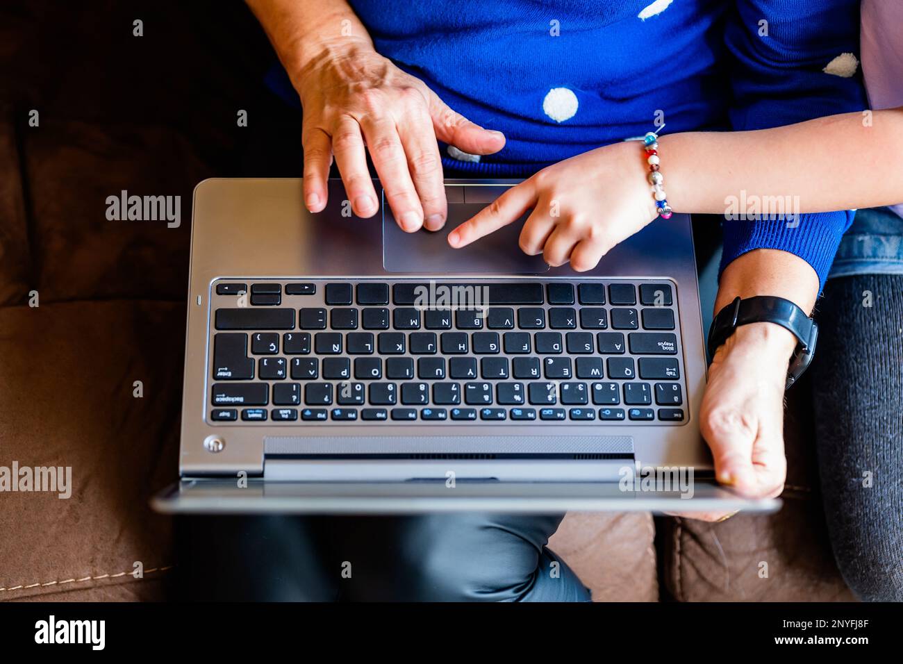 Vue de dessus de la femme sénior anonyme et enfant surfant sur Internet sur ordinateur portable tout en étant assis sur un canapé en cuir ensemble Banque D'Images