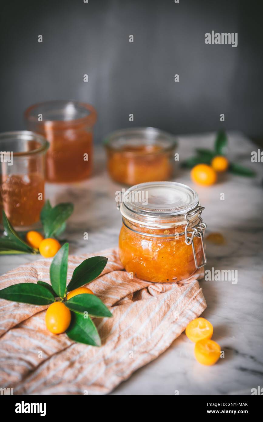 Bol en verre avec confiture de kumquat fraîche sur la table sur fond gris foncé flou Banque D'Images