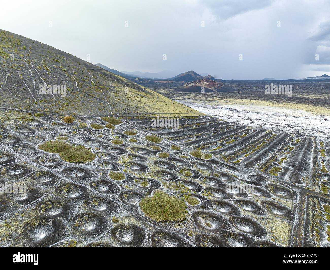 Vue aérienne de la viticulture sur le sol volcanique de lanzarot, île des Canaries, mettant en vedette la viticulture avec de petites fosses de collecte d'eau de pluie recouvertes de sel Banque D'Images