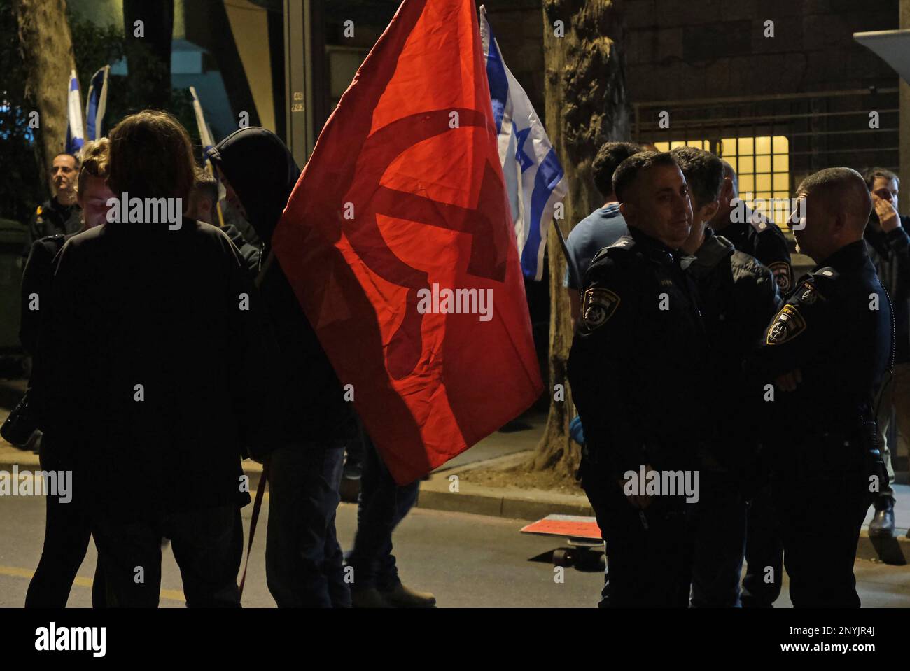 JÉRUSALEM, ISRAËL - MARS 1 : un manifestant anti-gouvernement détient le drapeau du mouvement communiste lors d'une manifestation contre le nouveau système judiciaire gouvernemental d'Israël près de la maison privée du Premier ministre Benjamin Netanyahu sur 1 mars, à Jérusalem, en Israël. Le gouvernement Netanyahou avance sur la proposition d'une refonte du système judiciaire qui limiterait la capacité de la Cour suprême israélienne à réviser et à faire tomber les lois qu'elle juge inconstitutionnelles. Crédit : Eddie Gerald/Alay Live News Banque D'Images