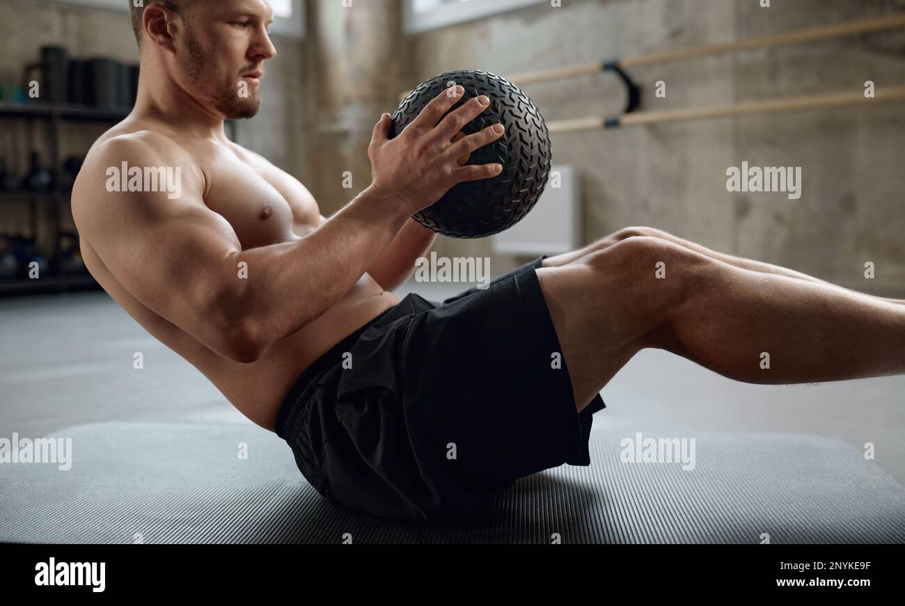 Homme faisant de l'exercice de forme physique, pratiquant l'exercice d'abs avec le ballon med dans la salle de gym Banque D'Images