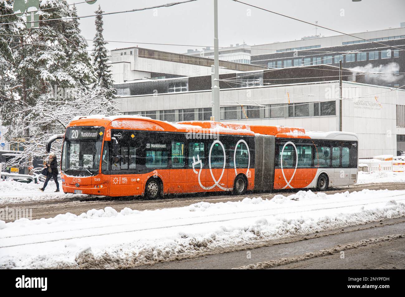 Bus électrique articulé sur la ligne 20 à l'arrêt de bus Haartmaninkatu lors d'une journée d'hiver grise dans le quartier de Meilahti à Helsinki, en Finlande Banque D'Images