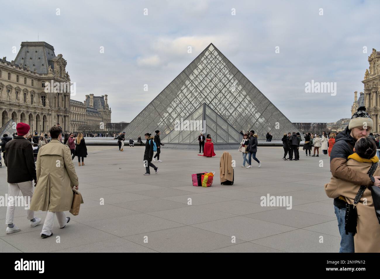 Inconnu couple eem être prêt pour un photoshoot habillé officiellement devant la pyramide de la lucarne en hiver. Paris Banque D'Images