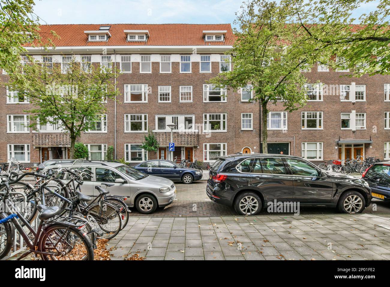 certaines voitures garées devant un bâtiment en briques avec de nombreuses fenêtres au dernier étage et dans la moitié inférieure du bâtiment Banque D'Images