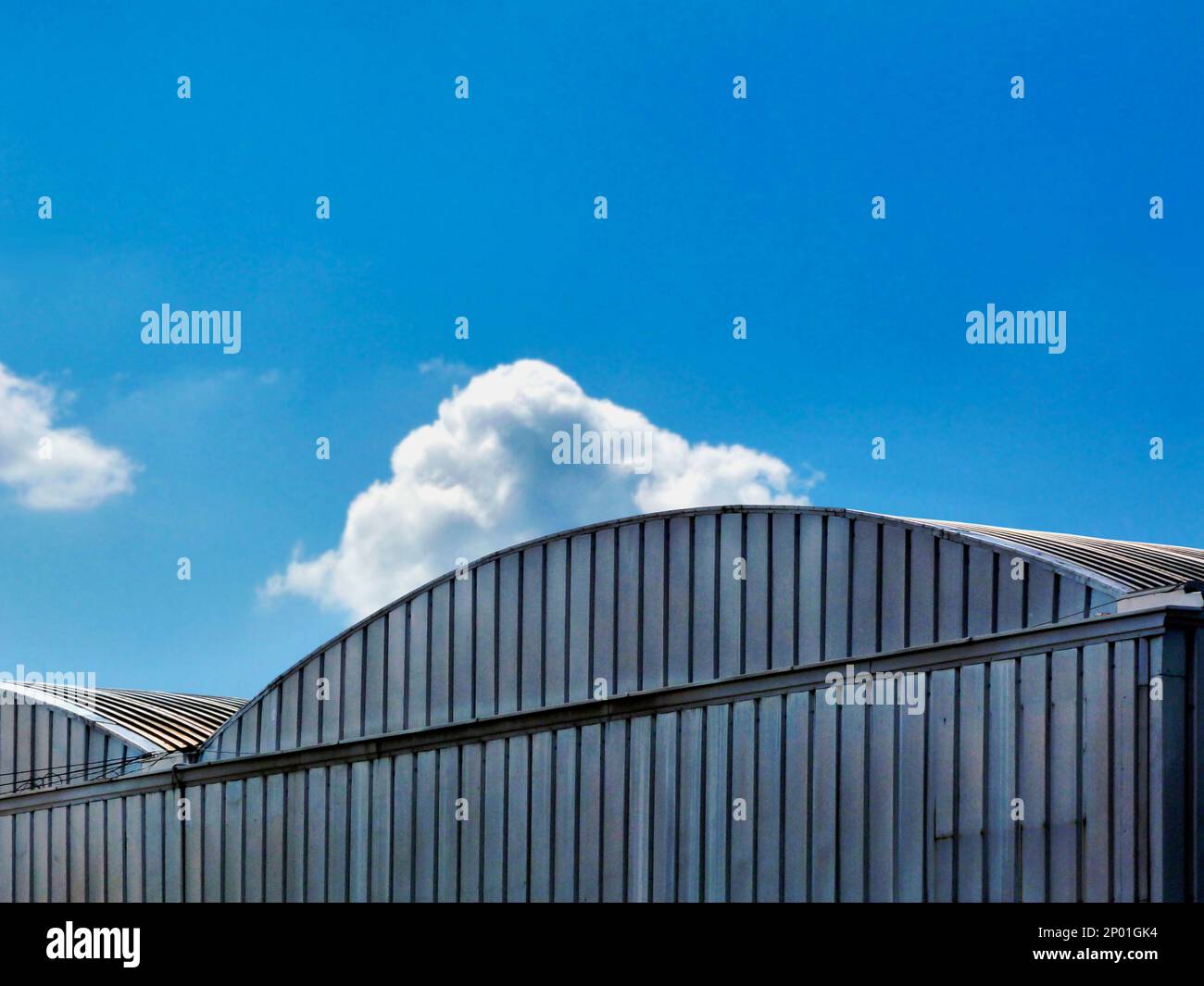 toit en hangar recouvert d'aluminium ondulé arqué. ciel bleu avec nuage blanc. vue à angle bas. design de type studio de film. concept studio de cinéma. Banque D'Images