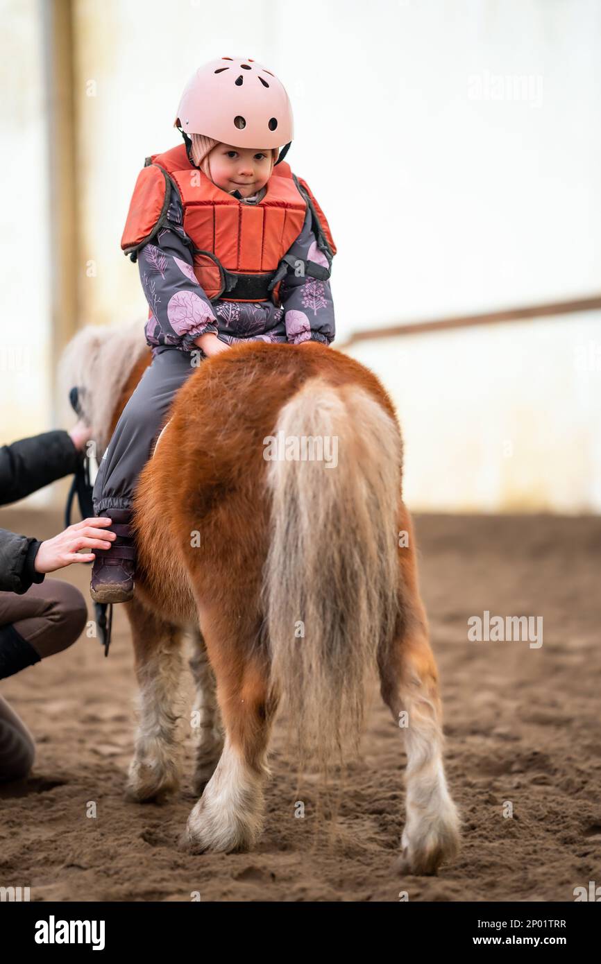 Leçon de équitation pour les petits enfants. Une jeune fille de trois ans fait du poney et fait des exercices Banque D'Images