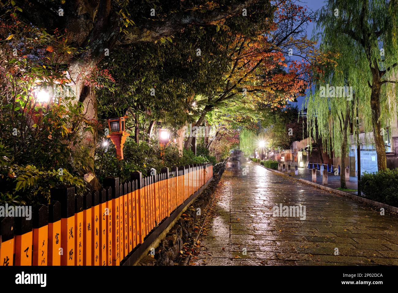 Une belle vue nocturne de la vermillon humide de la porte en bois orange et des pierres pavées d'une rue latérale à Kyoto, Japon Banque D'Images