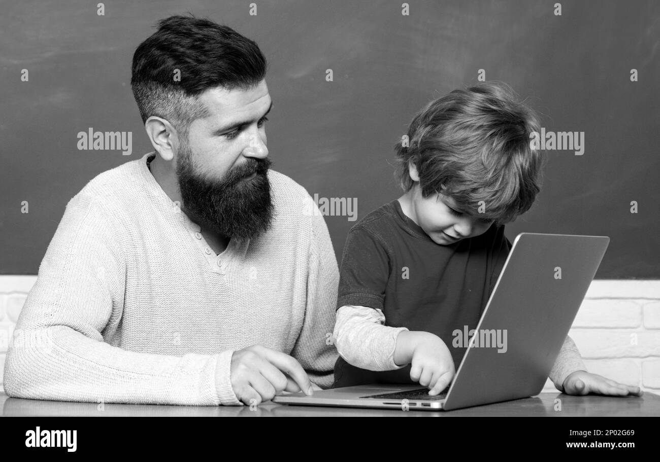 Un jeune garçon fait ses devoirs à l'école avec son père. Enseignant aidant le jeune garçon avec la leçon. Petits étudiants. Papa et son fils ensemble. Retour à l'école. Banque D'Images