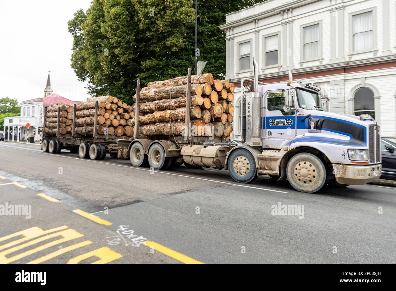 Camion-grumes traversant Graytown sur la State Highway 2, Nouvelle-Zélande. Camion et remorque Kenworth transportant des grumes forestières à travers la ville Banque D'Images