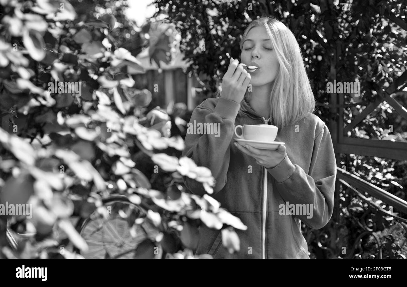 Hédonisme et gastronomie. Dégustez un délicieux cappuccino crémeux dans un jardin fleuri. Une fille boit un cappuccino gastronomique. Heure du café. La femme aime le goût divin de Banque D'Images