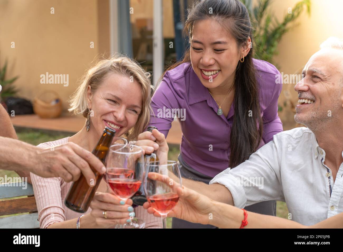 Gros plan d'un groupe d'amis joyeux qui se couchent avec un beau sourire autour de la table au restaurant de la maison sur le patio. Banque D'Images