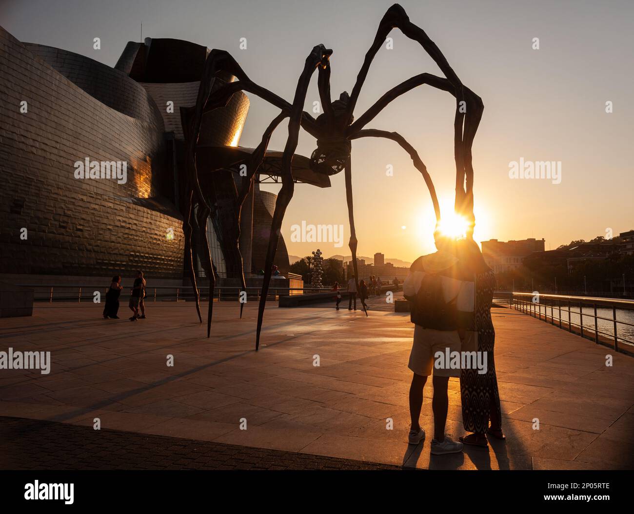 Bilbao, Espagne - 02 août 2022: Quelques touristes prennent un selfie au coucher du soleil à côté de l'araignée, la sculpture de Louise Bourgeois intitulée Mamam in Th Banque D'Images