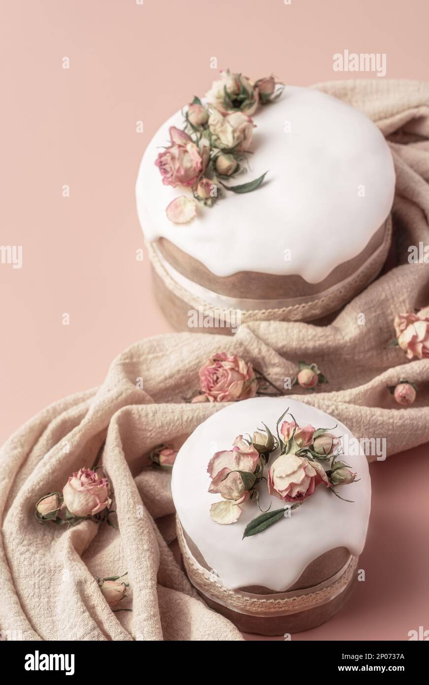 Gâteaux de Pâques émaillés décorés de fleurs de rose de thé sur fond pastel. Composition de Pâques avec gâteaux, roses et serviette. Arrière-plan de Pâques avec espace de copie pour votre conception. Banque D'Images