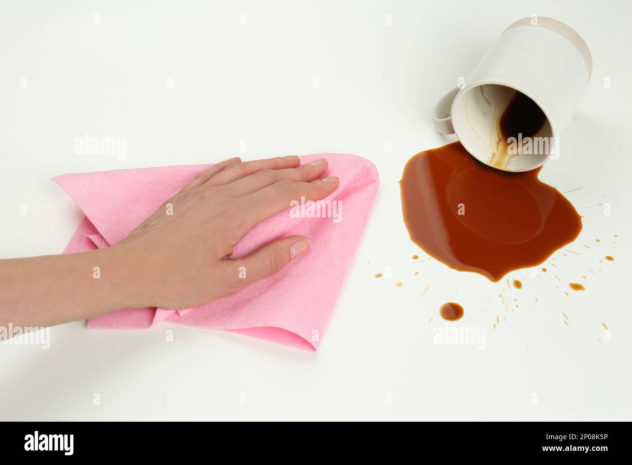Femme nettoyant le café renversé sur fond blanc, gros plan Banque D'Images
