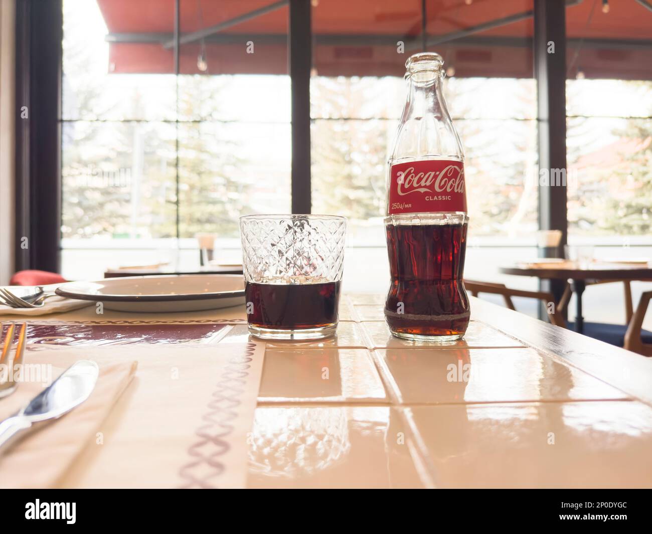 Erevan, Arménie, 28 février 2023: Photo de la boîte de Coca-Cola Classic bouteille de verre et tasse dans le restaurant. Bouteille de Coca-Cola et coca cola en verre. Banque D'Images