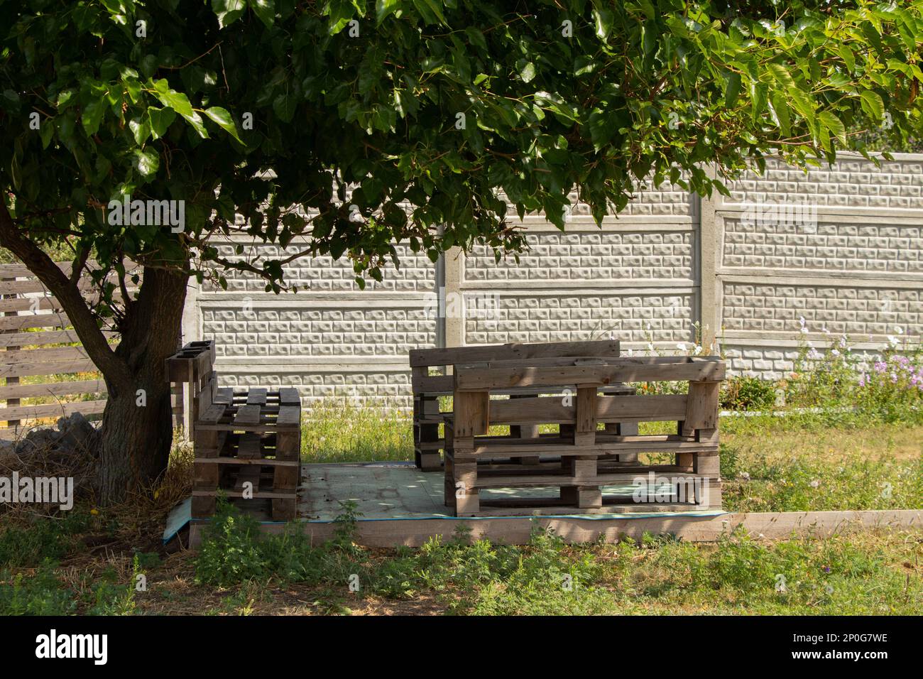 table de palette et chaises se tiennent dans le jardin sous un arbre, meubles de palette, robot manuel Banque D'Images