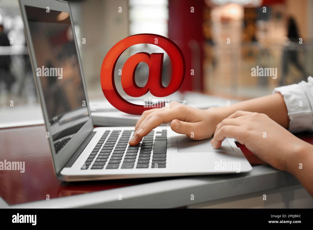 Femme envoyant un e-mail via ordinateur portable dans un café, gros plan Banque D'Images