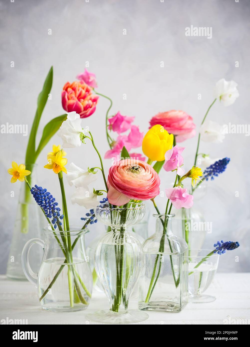 Belles bouquets de fleurs dans des vases en verre sur la table en bois.Tulips,roses,muscari, narcisse, eustoma et hyacinthes Banque D'Images