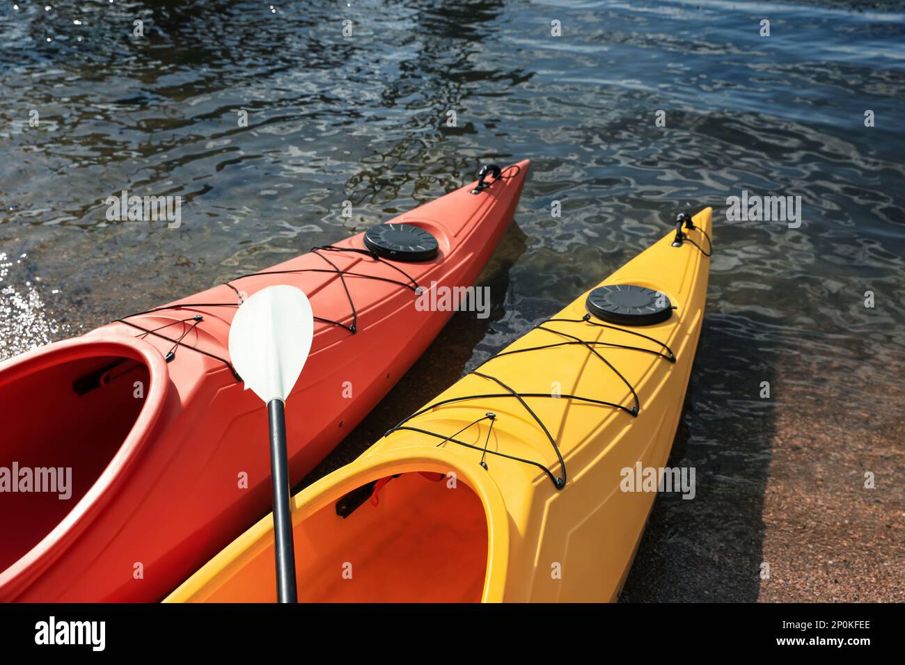 Kayaks modernes avec paddle sur la rivière, à proximité. Activité de camp d'été Banque D'Images Kayaks modernes avec paddle sur la rivière, à proximité. Activité de camp d'été Banque D'Images
