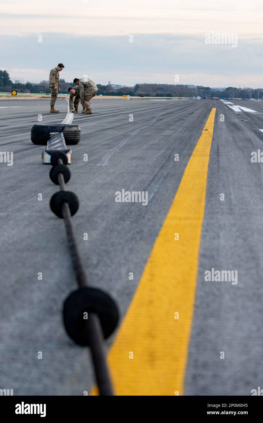 Les aviateurs de l'atelier de production d'énergie de l'escadron du génie civil 374th vérifient la partie en ruban de nylon d'un système d'arrêt d'avion (AAS) pour détecter toute usure ou dommage éventuel à la base aérienne de Yokota, Japon, le 6 janvier 2023. Les AAS sont inspectés pour s'assurer qu'il n'y a pas de bandes de nylon déchirées, de coupures dans le câble en acier, de fuites hydrauliques ou de débris causés par la prise d'avions à grande vitesse lorsqu'ils atterrissent. Banque D'Images