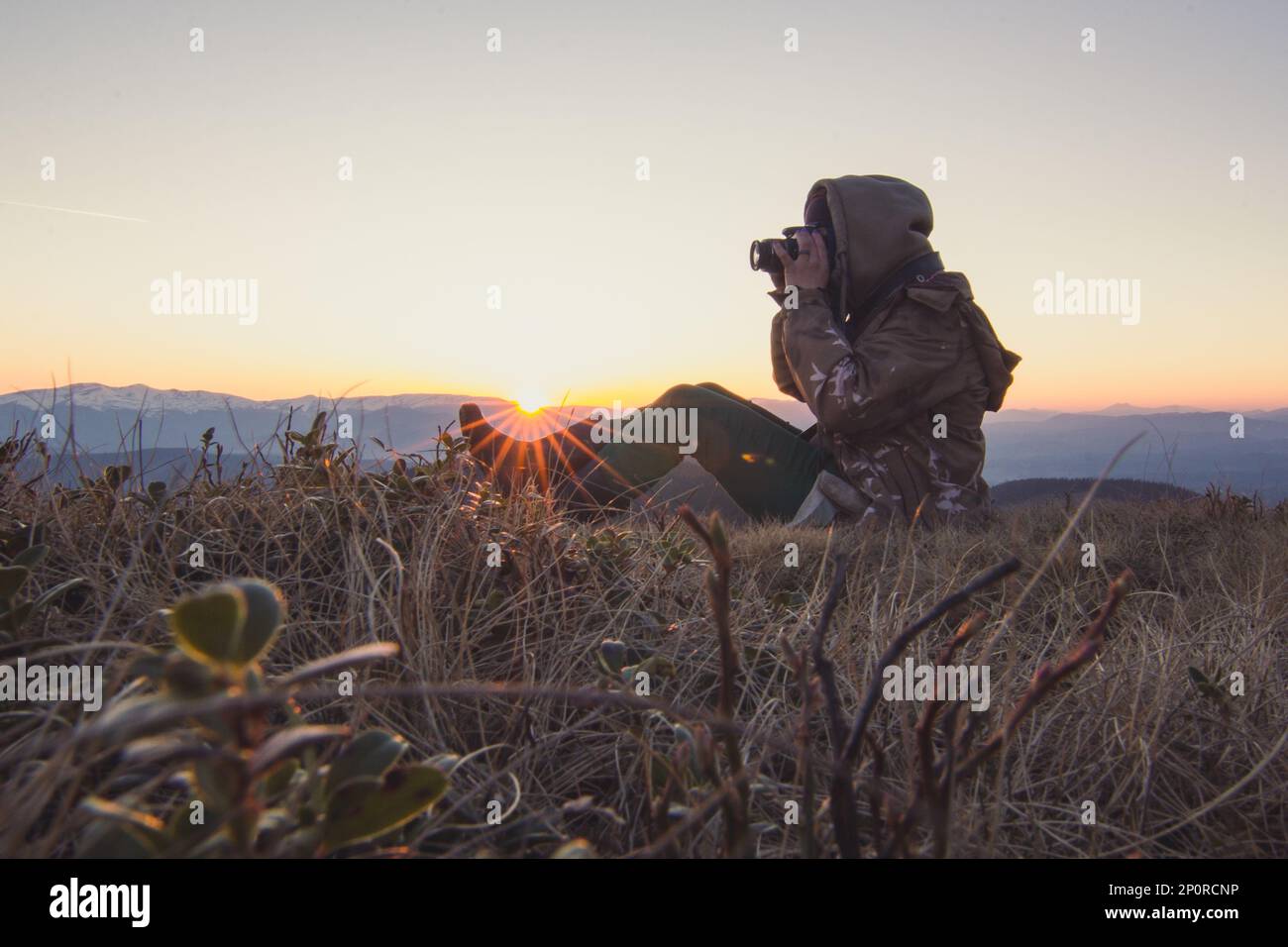 Photographe de randonnée faisant des photos de coucher de soleil dans les montagnes pittoresques Banque D'Images