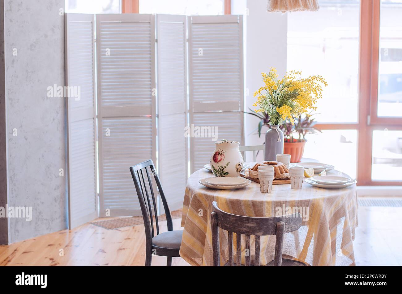Printemps, Pâques à l'intérieur dans le style scandinave. Salon rustique avec une armoire lumineuse, vase jaune mimosa. La table est fixée avec ceram Banque D'Images