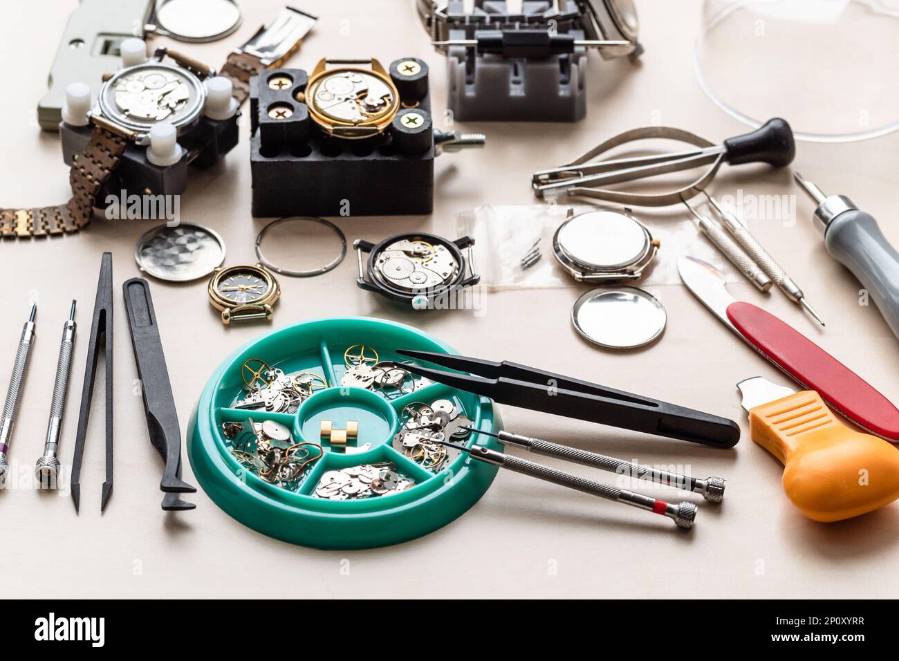pièces de rechange, outils et montres utilisées sur une table en bois dans un atelier horloger Banque D'Images